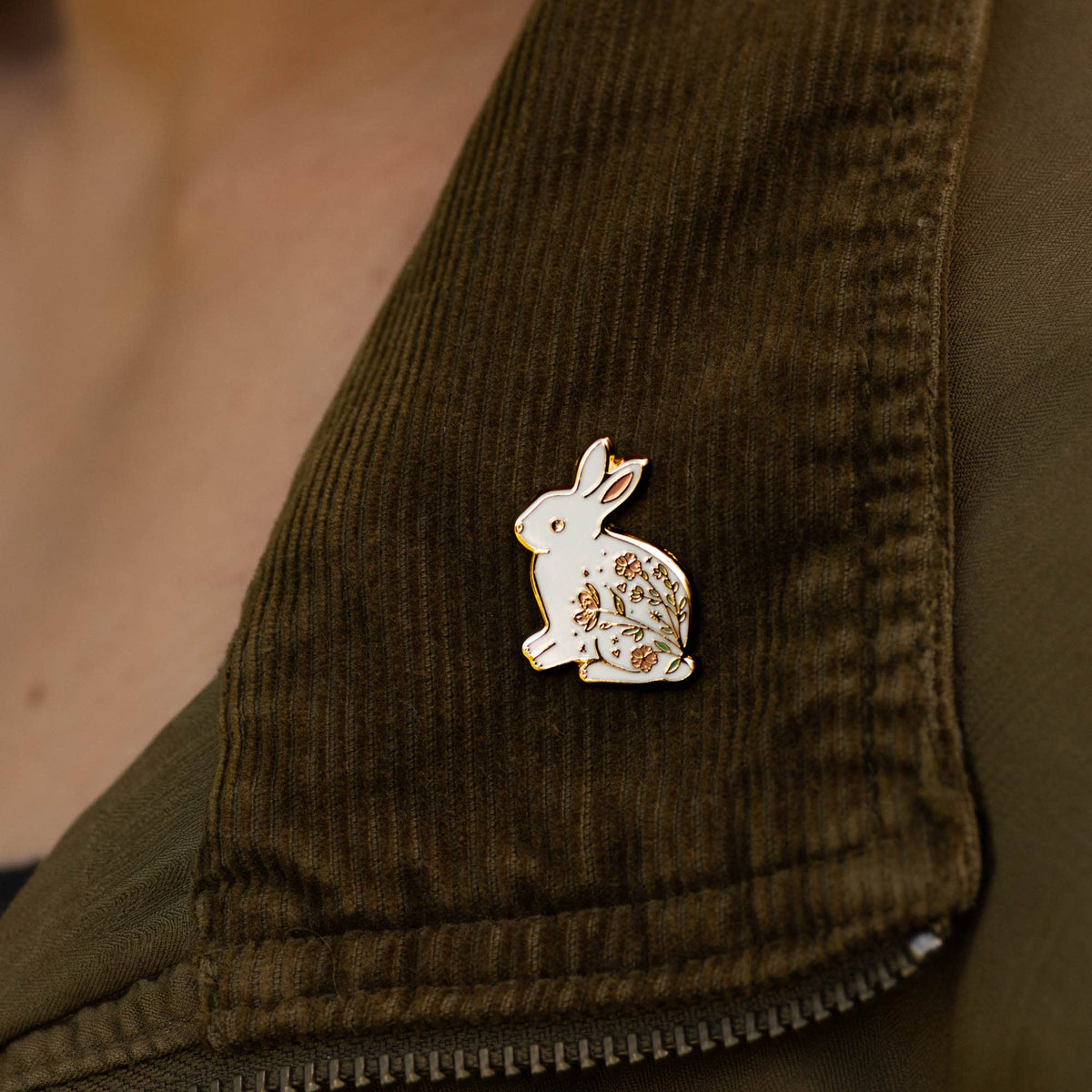 Rabbit enamel pin on olive corduroy fabric, white and gold with floral detail