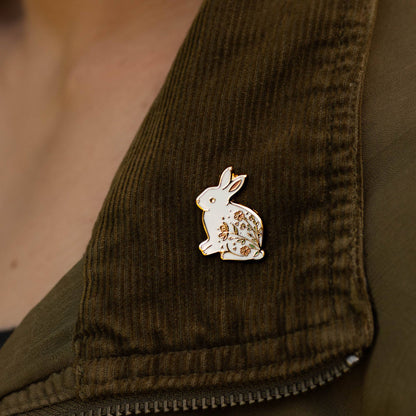 Rabbit enamel pin on olive corduroy fabric, white and gold with floral detail