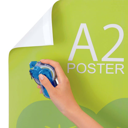 Hand using blue tape dispenser to apply adhesive tape to poster board