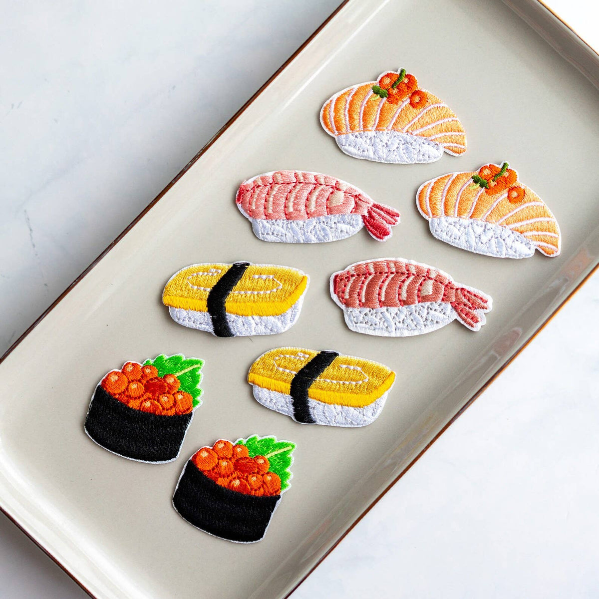 Sushi iron-on patch assortment on tray: salmon, shrimp, omelette, and roe pot