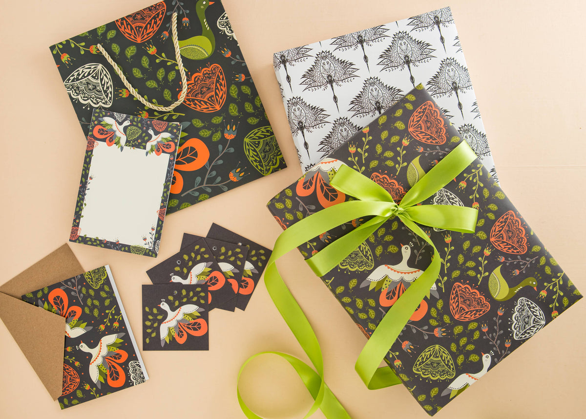 Floral notepad with bird and leaf motifs, shown among matching stationery and a green ribbon
