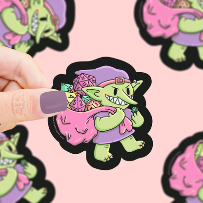 Goblin dice vinyl sticker showing a goblin holding colorful dice, die-cut on black backing.