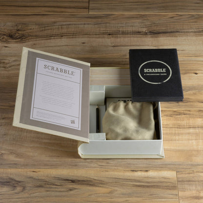 Open Scrabble game box with instruction sheet pages and black game cover