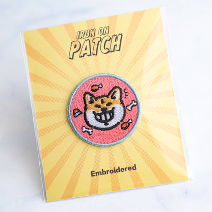 Round embroidered dog iron-on patch with smiling white dog face on pink