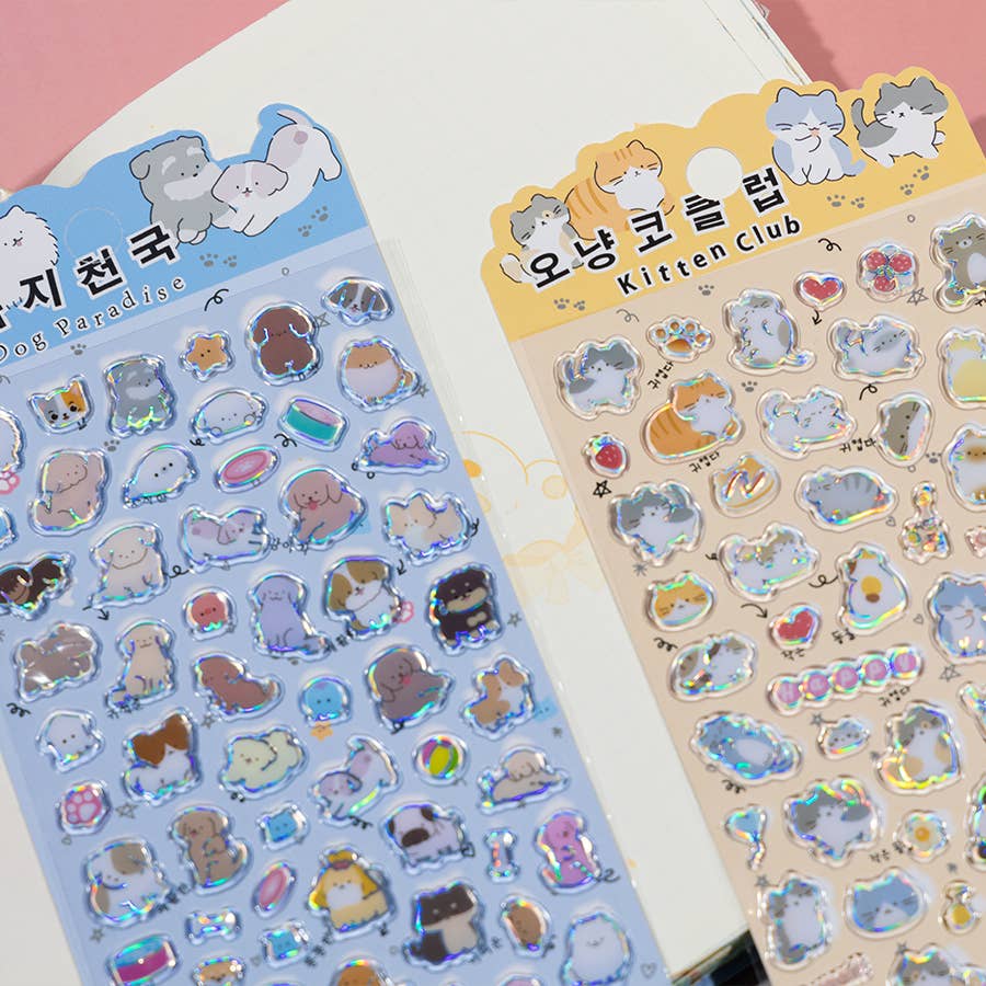 Close-up of blue and beige sticker sheets showing cartoon cats, animals, and shiny icons.