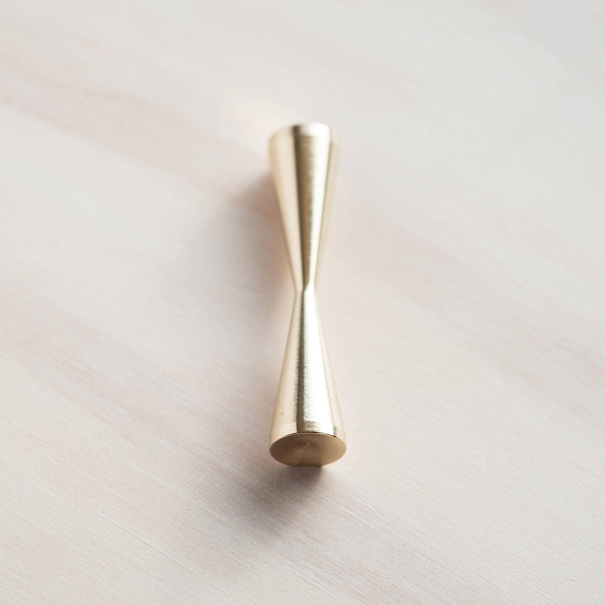 Gold brass pen rest base with narrow pointed top and rounded bottom