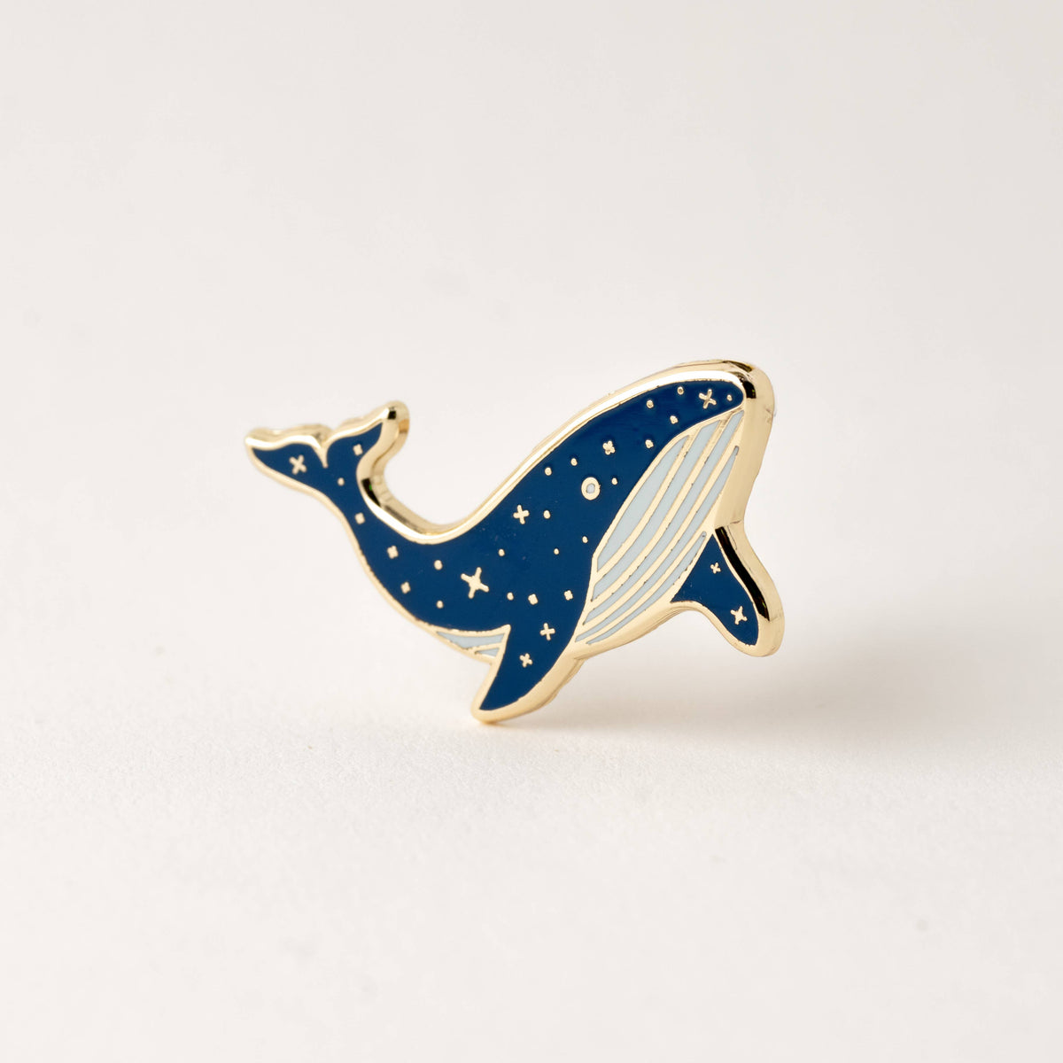 Blue whale enamel lapel pin with gold outline and star details