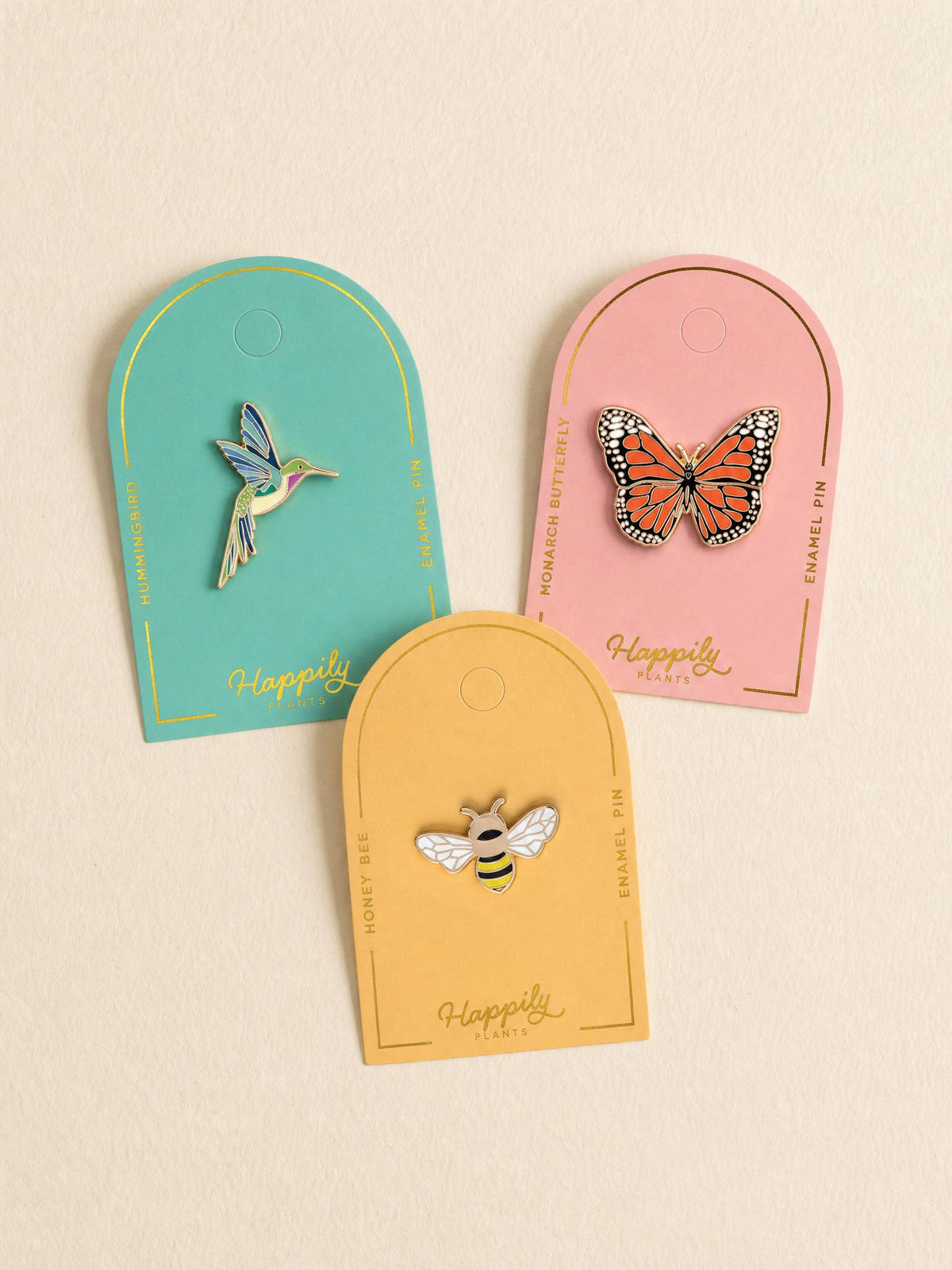 Monarch butterfly pins on three hanging gift cards in teal, pink, and tan.