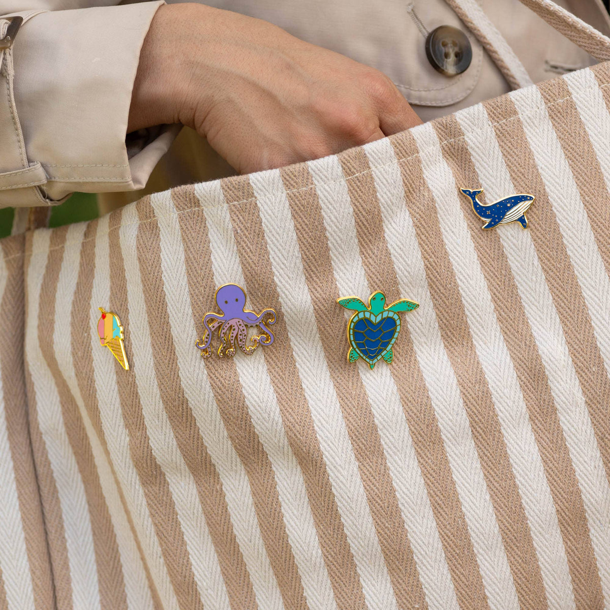 Blue whale enamel pin on striped fabric shirt collar