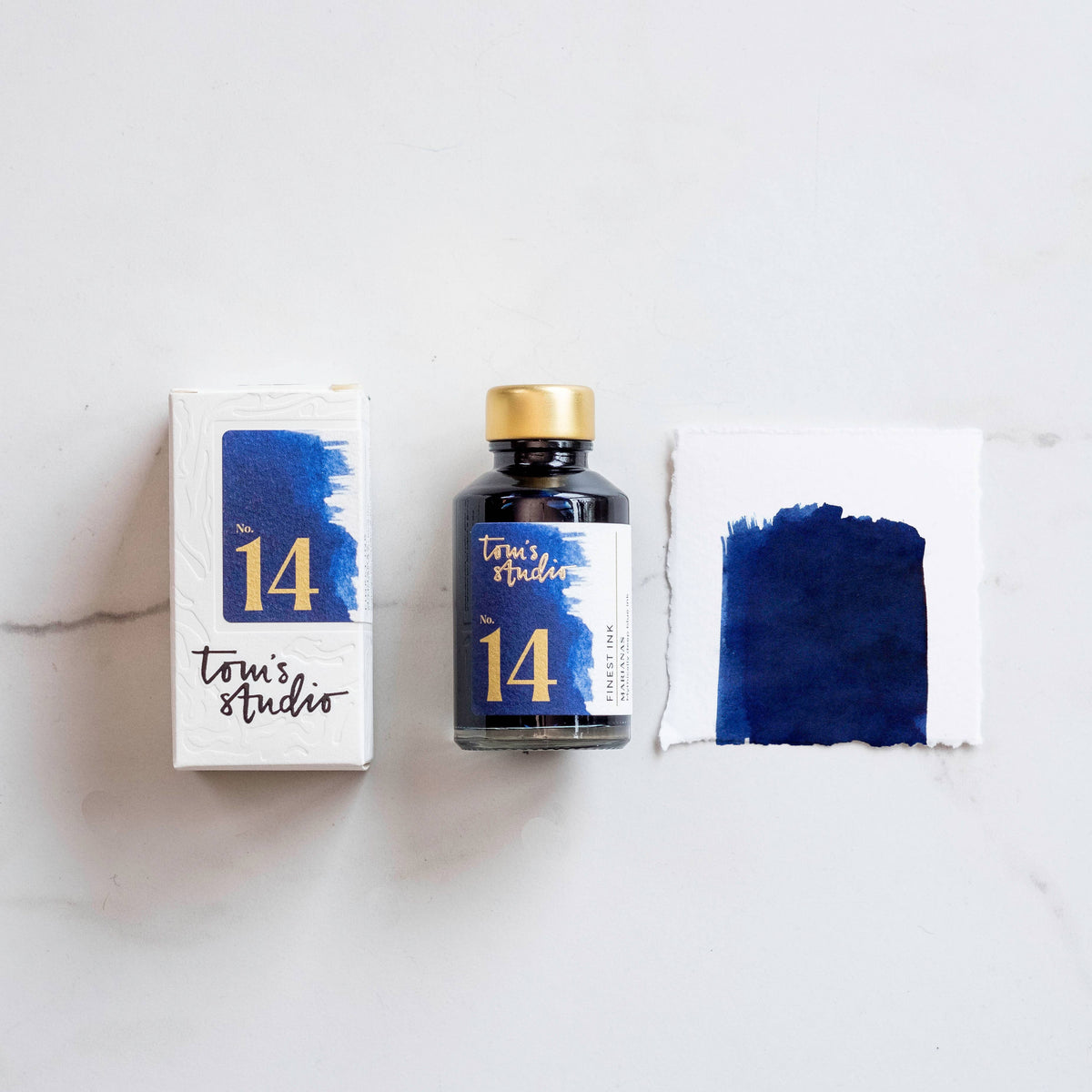 Fountain pen ink bottle in Marianas deep blue with ink blot on paper