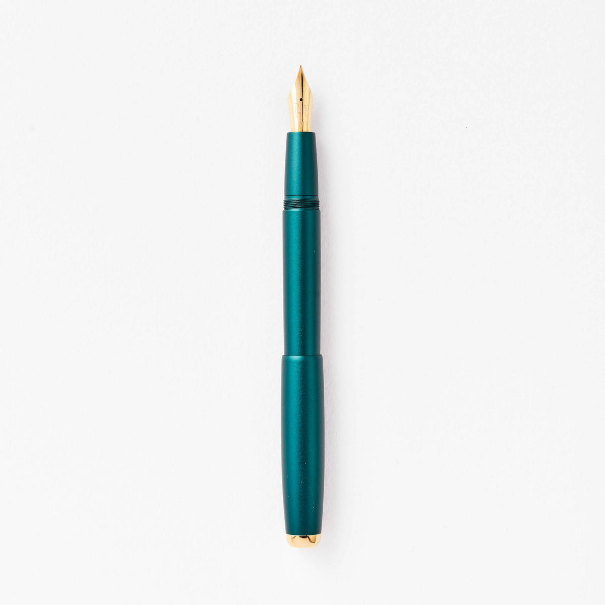 Teal green fountain pen with gold nib, shown upright