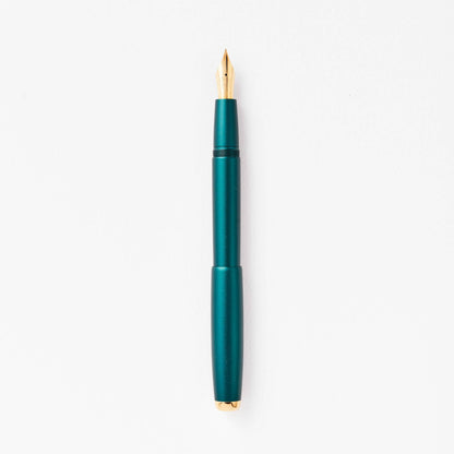 Teal green fountain pen with gold nib, shown upright
