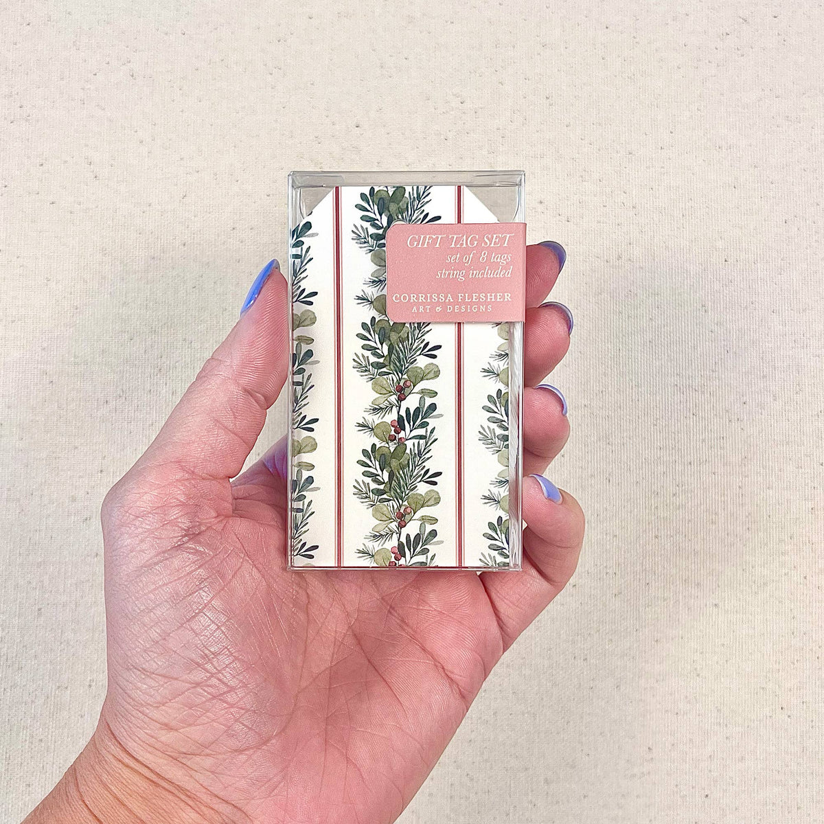 Hand holding Christmas gift tag set package with greenery and berries tag design