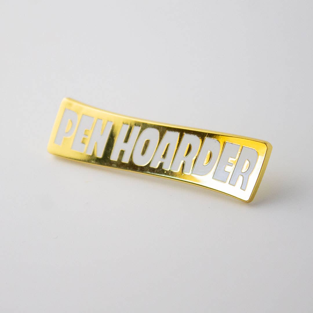 Rectangular gold enamel pin with 'Pen Hoarder' title