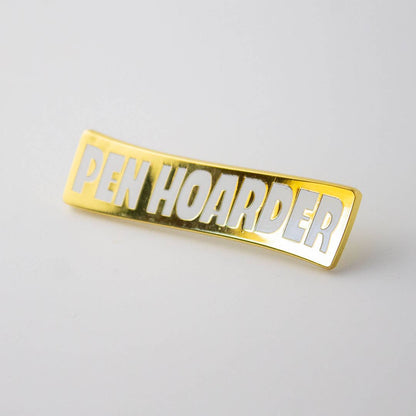 Rectangular gold enamel pin with 'Pen Hoarder' title