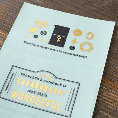 Charm icon sticker sheet with airplane, key, and “Every Traveler’s notebook is unique” text