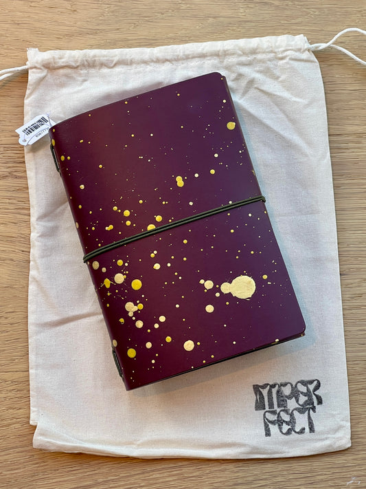 Maroon painted notebook with gold speckle dots and dark elastic band