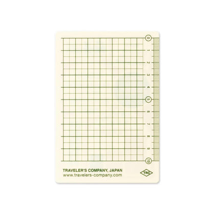 Passport-size plastic pencil board with a green grid and measuring rulers