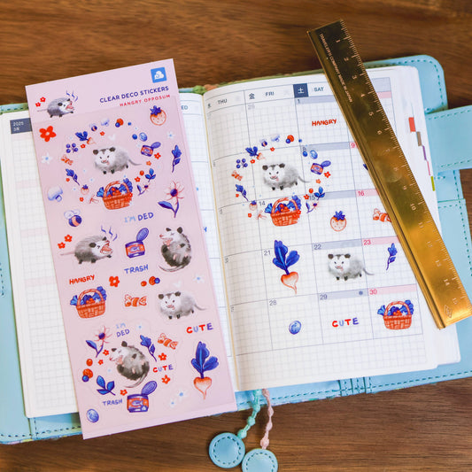 Clear sticker sheet with grid layout, opposum stickers, flowers, and 'CUTE' labels