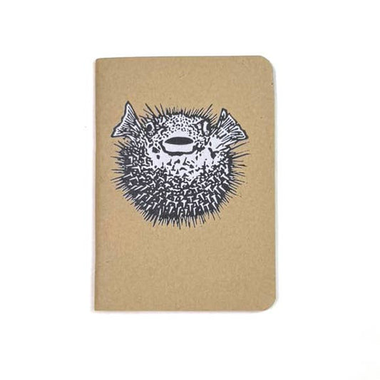 Small softcover notebook with tan cover and black fish face graphic