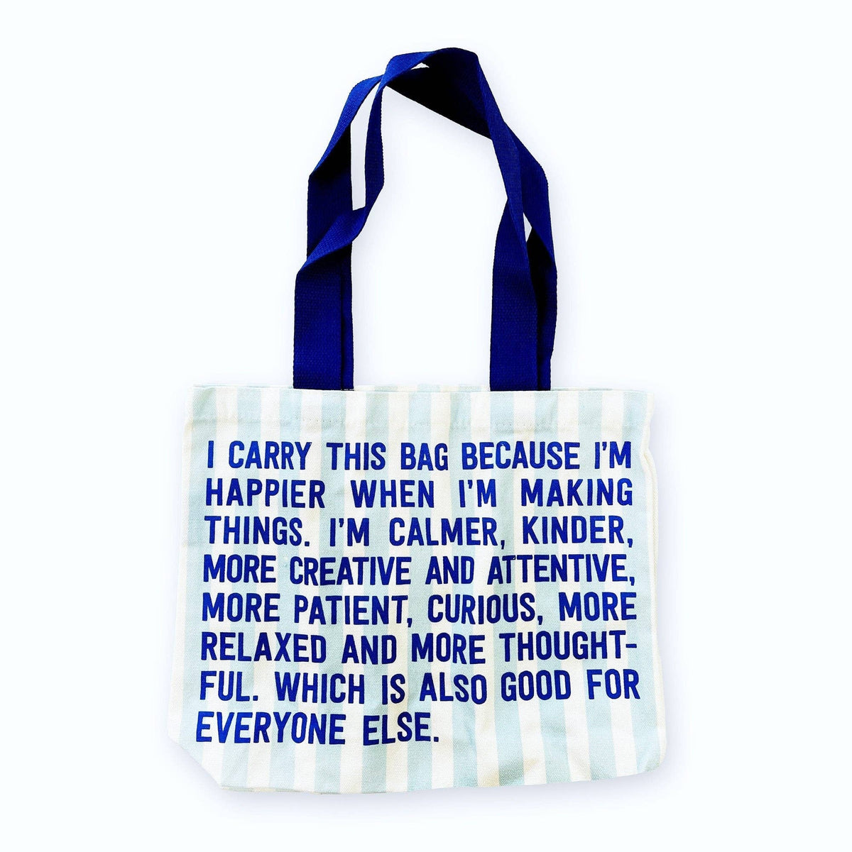 Canvas tote bag with blue handles and bold quote text on light striped fabric.