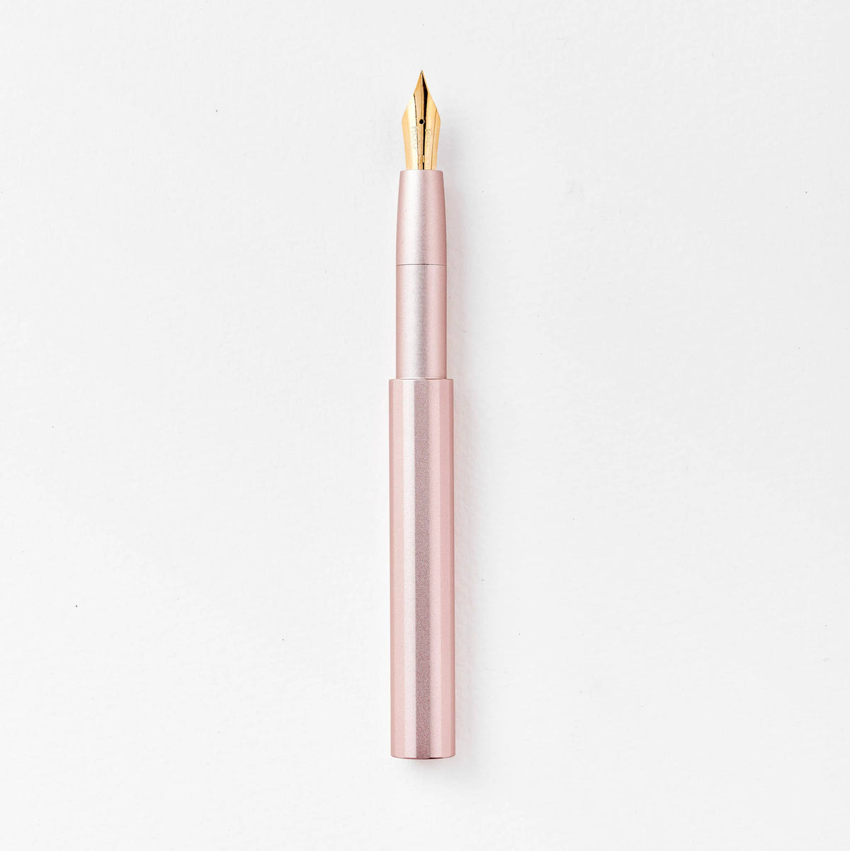 Blush pink pocket fountain pen with gold nib, uncapped.