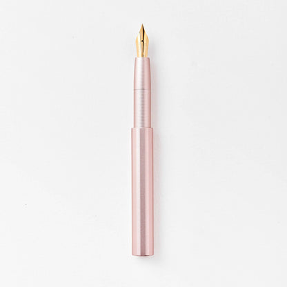 Blush pink pocket fountain pen with gold nib, uncapped.