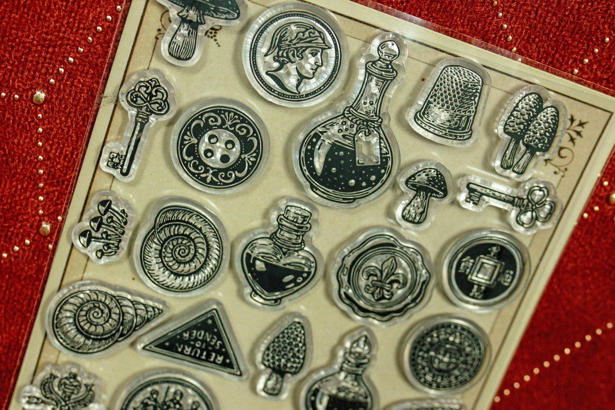 Clear acrylic stamp set close-up with coins, keys, bottles, cactus and gear icons