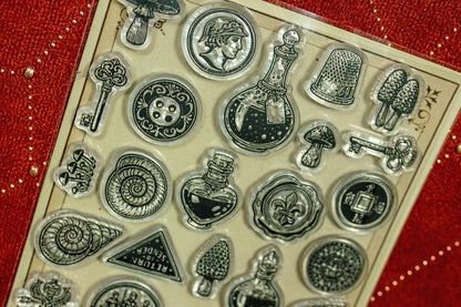 Clear acrylic stamp set close-up with coins, keys, bottles, cactus and gear icons