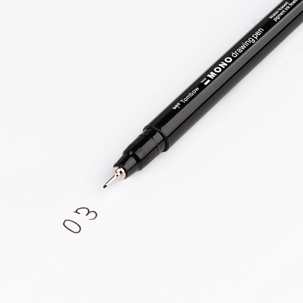 Black fine-tip drawing pen writing a small “0.3” sketch on white paper