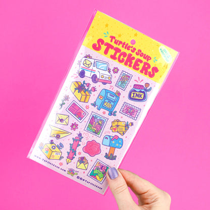 Hand holding glitter sticker sheet with postage and ink-themed icon designs