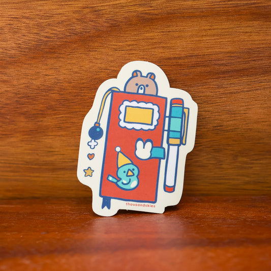 Colorful robot and notebook die-cut vinyl sticker with pens, white border