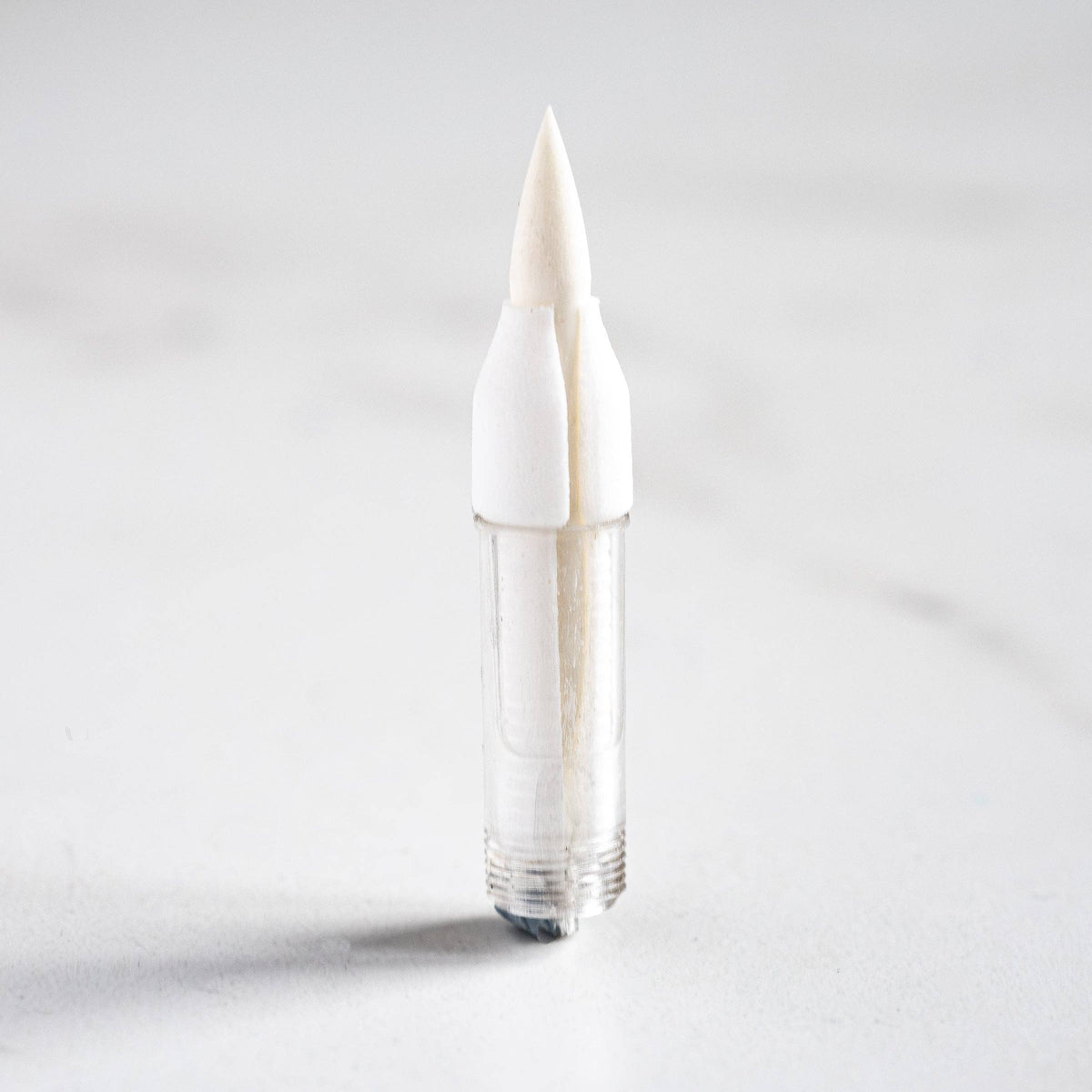 White brush tip pen with fine pointed bristles, no cap visible
