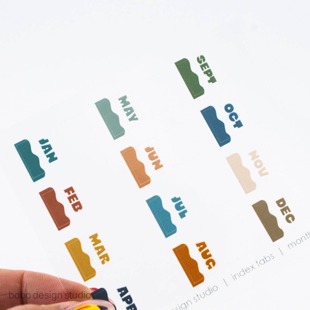 Colorful month index sticker tabs arranged: JAN, FEB, MAR, APR, MAY, JUN, JUL, AUG, SEP, OCT, NOV, DEC