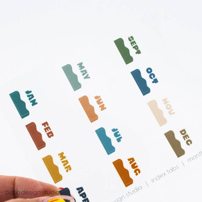 Colorful month index sticker tabs arranged: JAN, FEB, MAR, APR, MAY, JUN, JUL, AUG, SEP, OCT, NOV, DEC