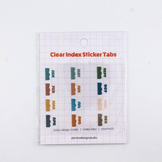 Clear planner index sticker tabs with colorful month labels on a transparent sheet