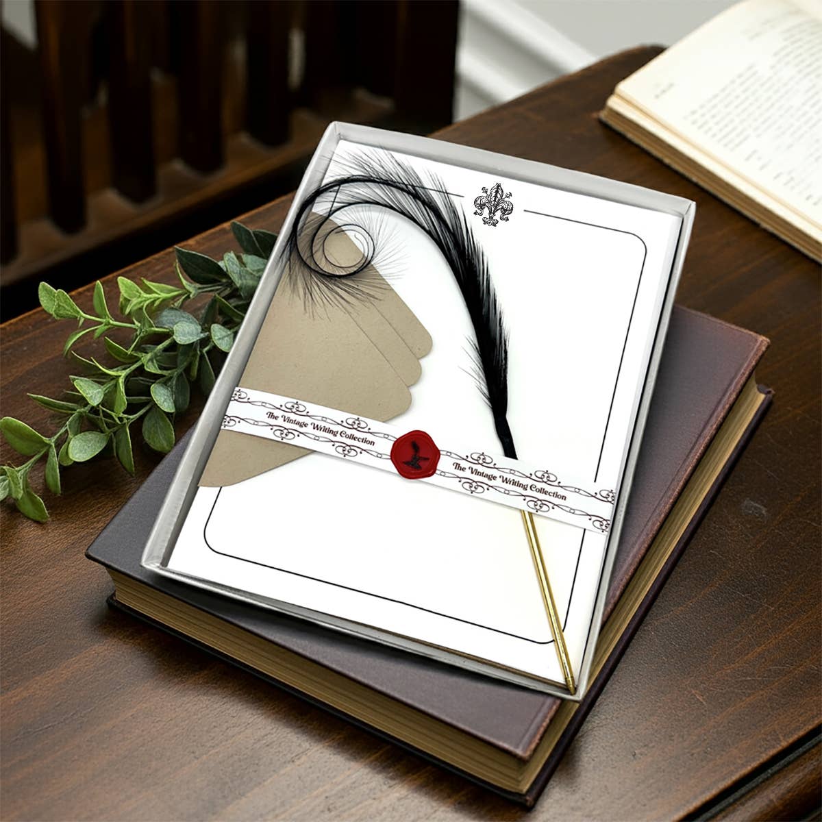 Letterpress stationery set in open box with curled feather pen, wax seal, and blank card panels