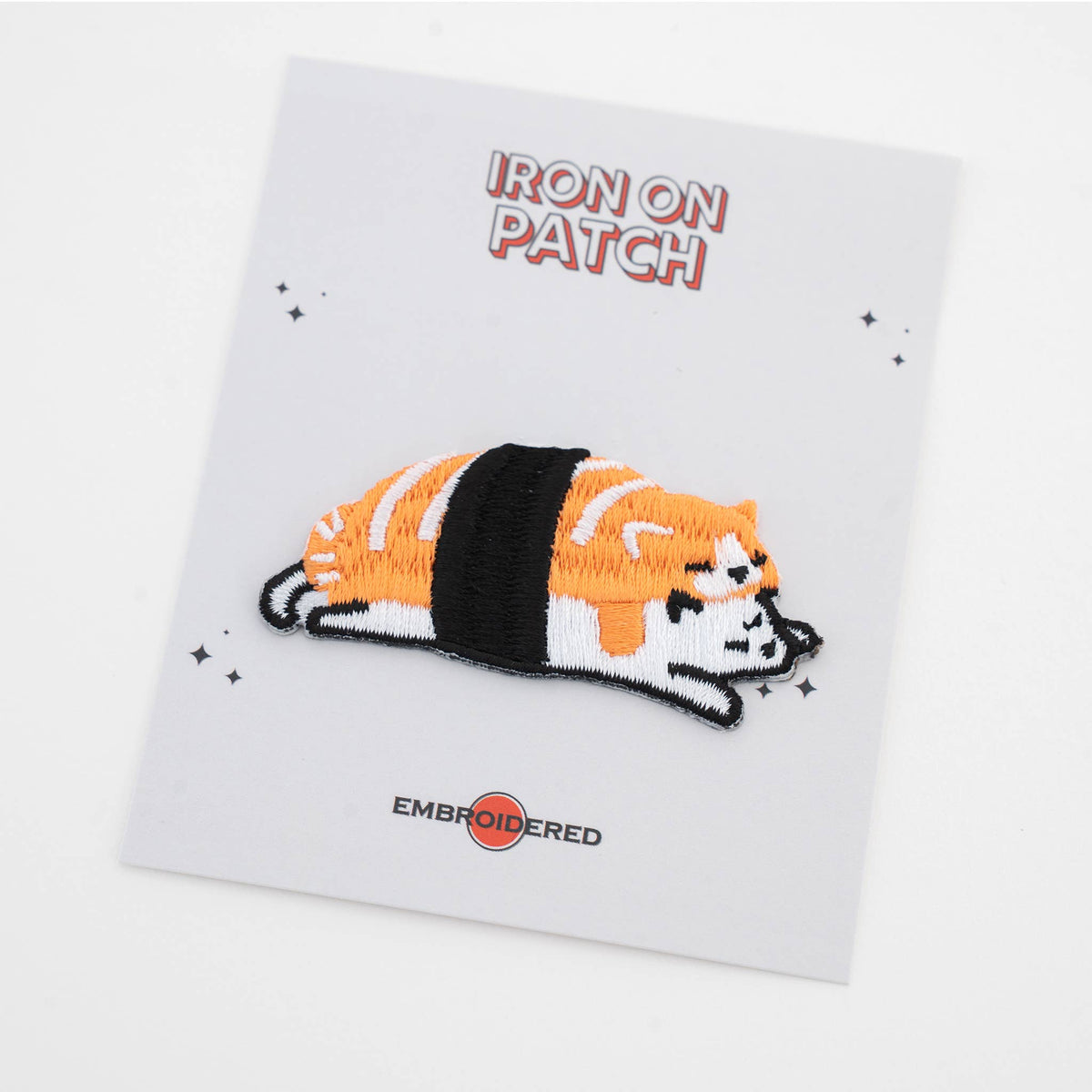 Iron-on cat food patch: striped orange and black cat lying on sushi roll, embroidered detail
