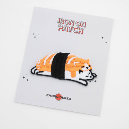 Iron-on cat food patch: striped orange and black cat lying on sushi roll, embroidered detail