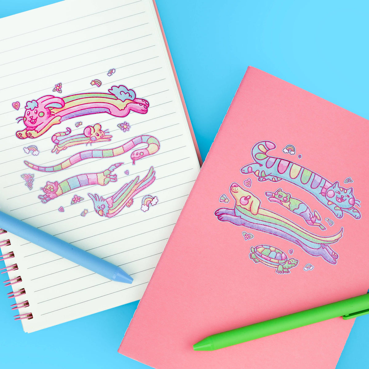 Pink and blue notebooks beside a rainbow animal glitter sticker sheet