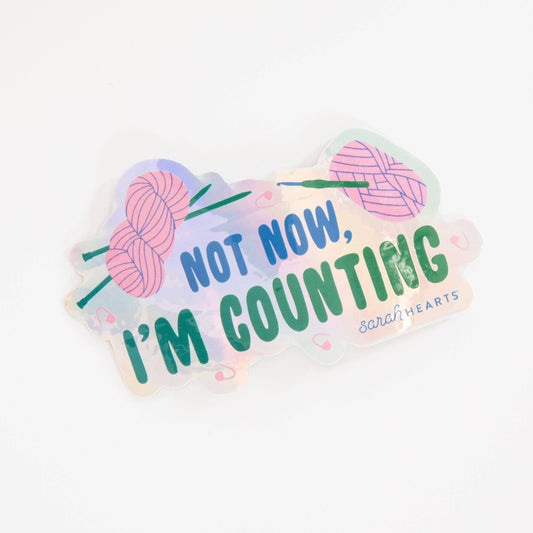 Pink holographic sticker: “Not Now, I’m Counting” with yarn balls and green lettering