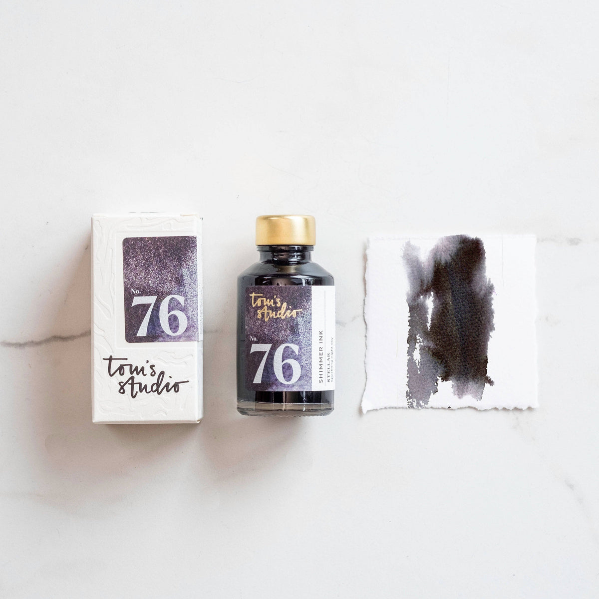 Shimmer ink bottle with metallic purple swatch and ink box, gold cap