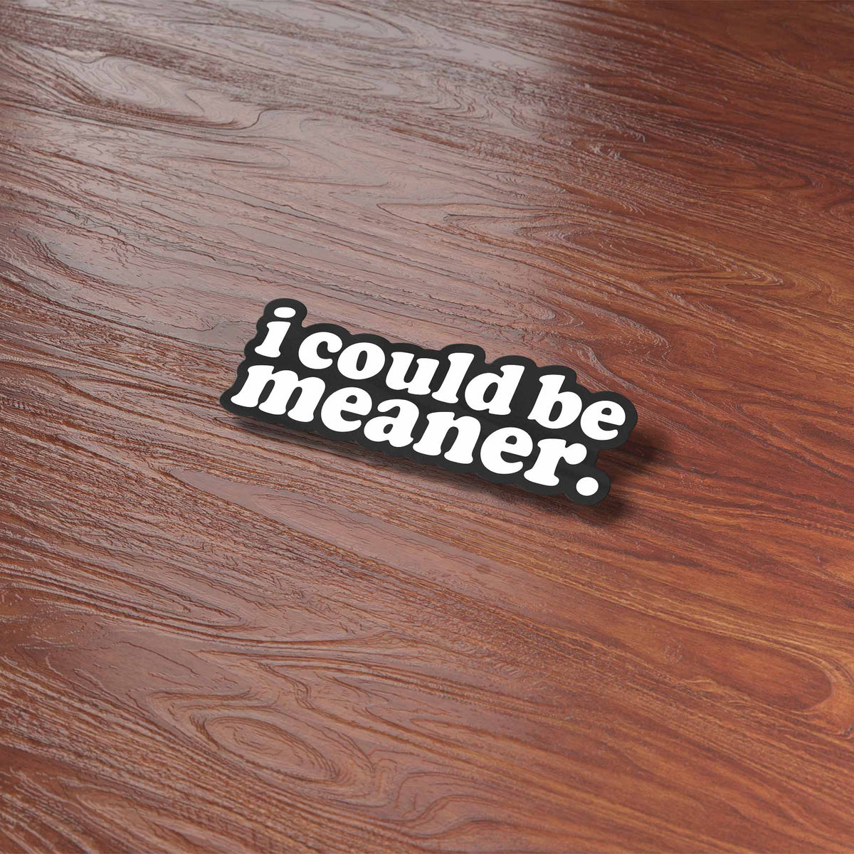 Funny quote sticker reading "i could be meaner." on a wooden table