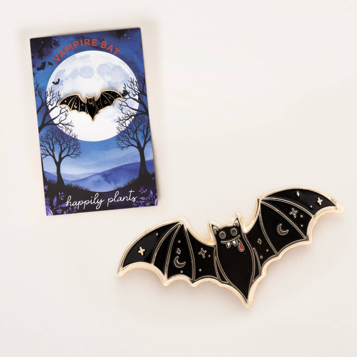 Vampire bat enamel lapel pin with black wings beside a gift card