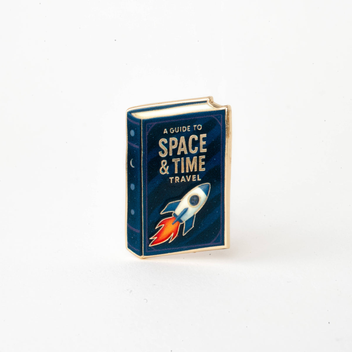 Enamel book pin with rocket on blue “Space & Time Travel” cover.