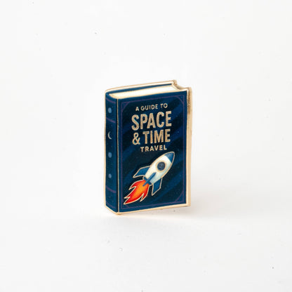 Enamel book pin with rocket on blue “Space & Time Travel” cover.