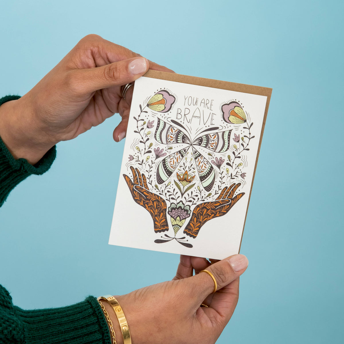 Greeting card held upright, featuring a detailed butterfly and floral design.