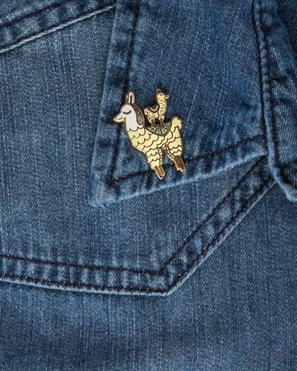 Mama Llama enamel pin with a small llama riding on its back, shown on a denim pocket.