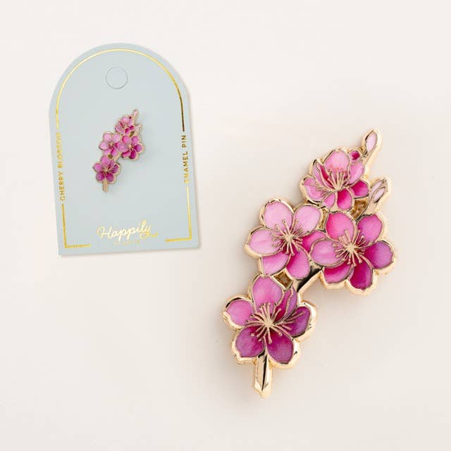 Pink cherry blossom enamel pin with gold-tone details shown with hanging card