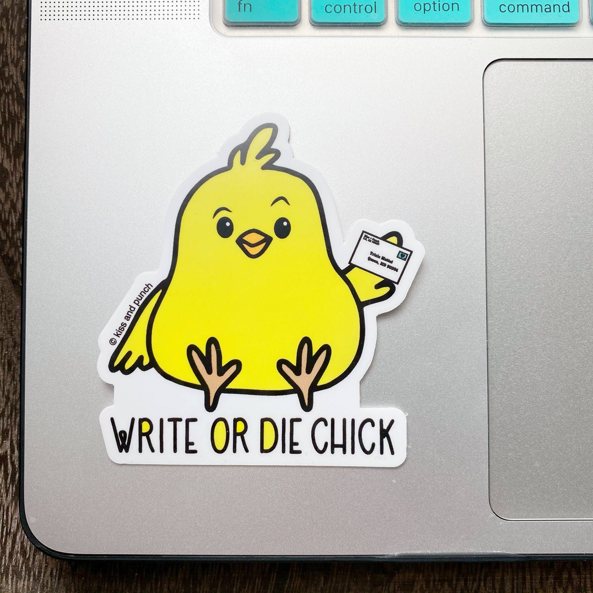 Yellow chick vinyl sticker with “Write or Die Chick” lettering, displayed on a laptop